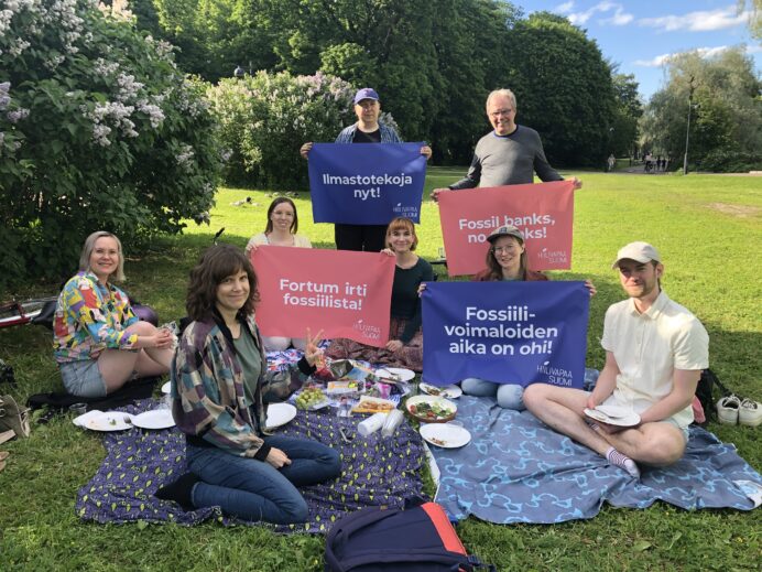 7 kampanjan aktiivia piknikillä pitelemässä Hiilivapaa Suomen banderolleja